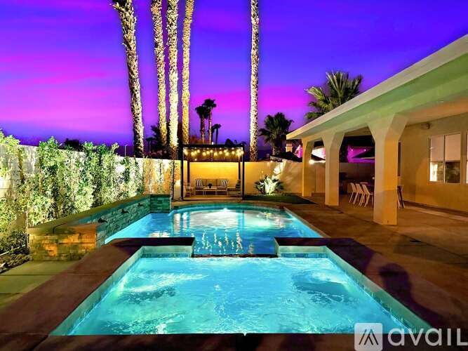 A pool surrounded by a stone wall and palm trees.