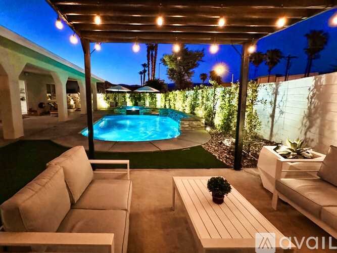 A pool surrounded by a patio with couches and a table.