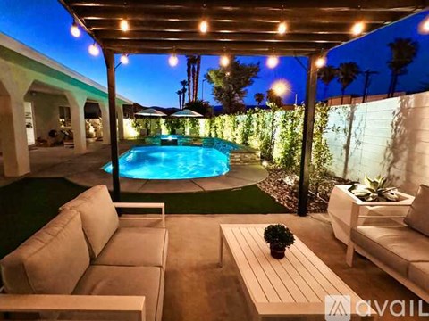 A pool surrounded by a patio with couches and a table.