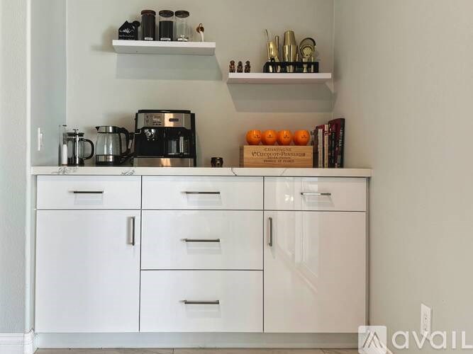 A kitchen with white cabinets and shelves holding various items.