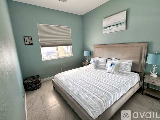 A bedroom with a large bed and a window with blinds.