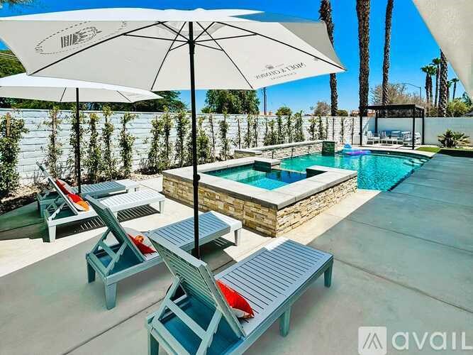 A pool area with lounge chairs and an umbrella.