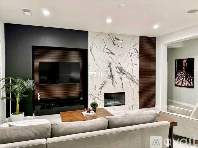 A modern living room with a grey sofa, a fireplace, and a TV.