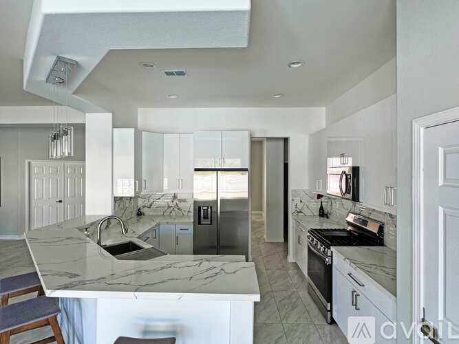 A modern kitchen with a marble countertop and stainless steel appliances.