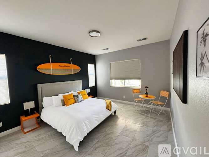 A bedroom with a large bed and a surfboard on the wall.