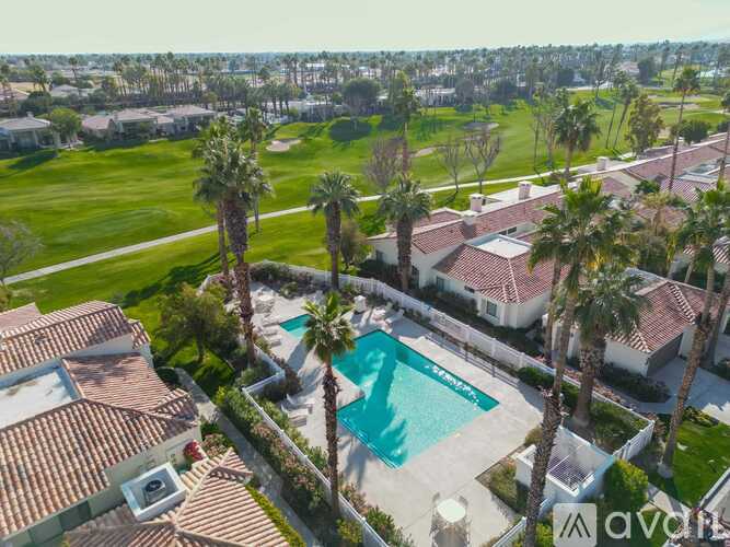 A large house with a pool surrounded by palm trees.