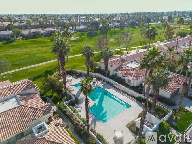 A large house with a pool surrounded by palm trees.