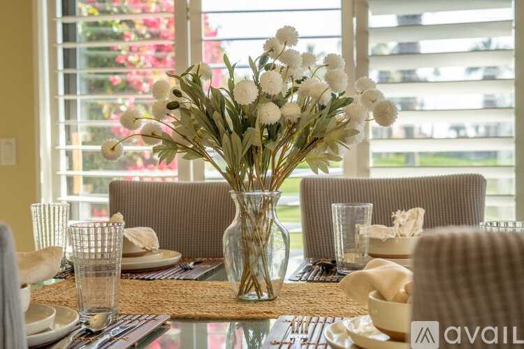 A table set for a meal with a vase of white flowers in the center.