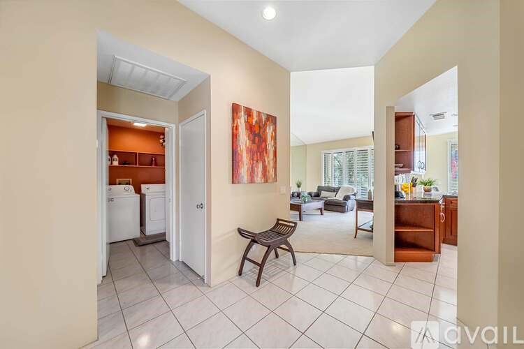 A kitchen with a refrigerator, a dining table with chairs, and a painting on the wall.