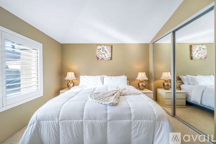 A bedroom with a large bed and a mirror on the wall.
