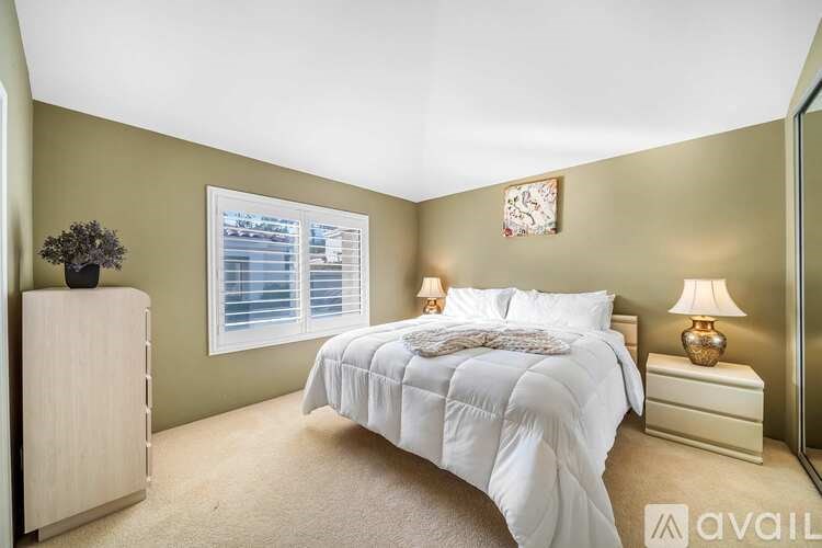 A bedroom with a large bed and a wooden dresser.
