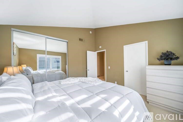 A bedroom with a large bed and a mirror on the wall.