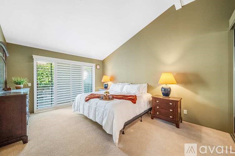 A bedroom with a bed, nightstand, and window with blinds.