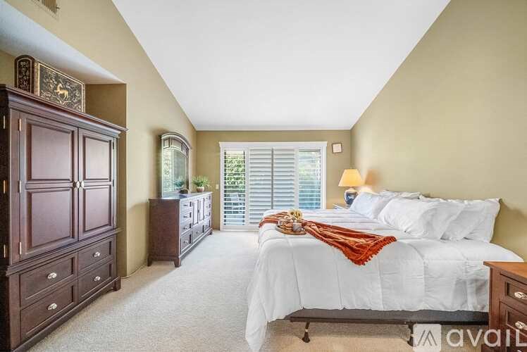 A bedroom with a bed, dresser, and window with blinds.