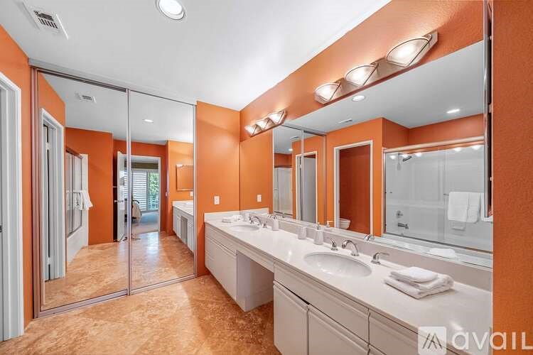 A bathroom with orange walls and a large mirror.