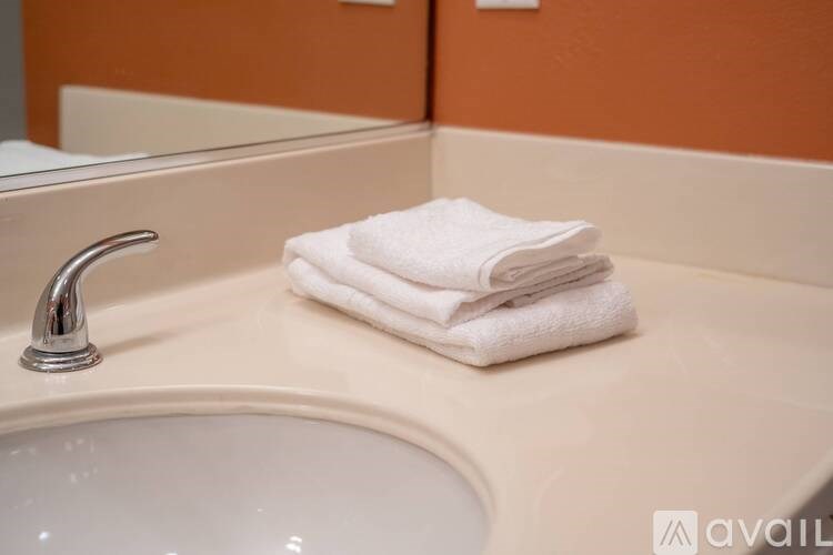 A stack of white towels sits on a bathroom sink.