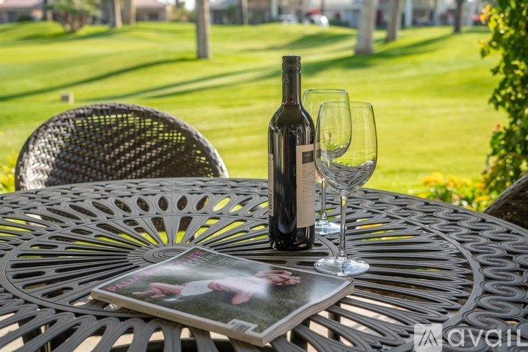 A bottle of wine and a glass are on a table with a magazine.