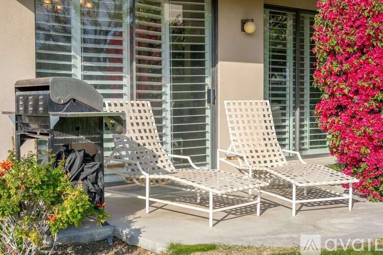Two white chairs are placed on a patio.
