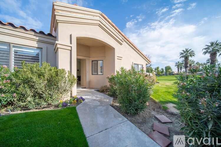 A house with a beige exterior and a green lawn in front.
