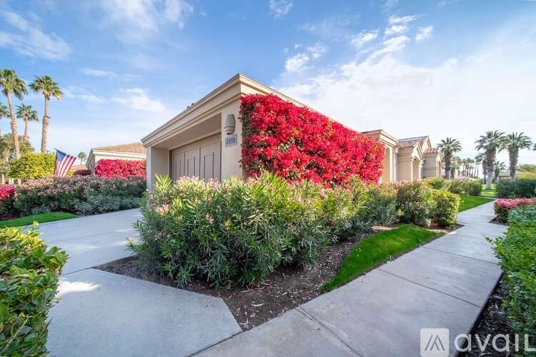 A house with a red flower wall in front.