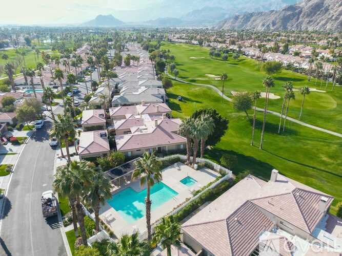 A bird's eye view of a residential area with houses, a pool, and a golf course.