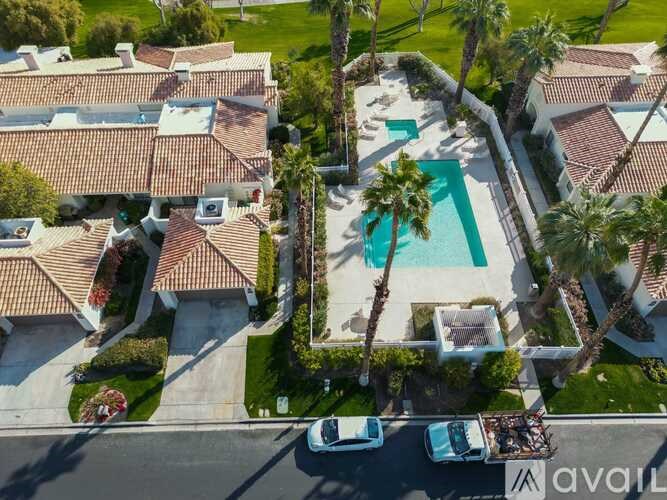 A bird's eye view of a residential area with a swimming pool and palm trees.