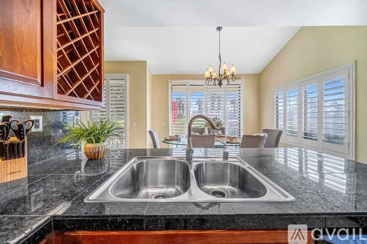 A kitchen with a black granite countertop and a double sink.