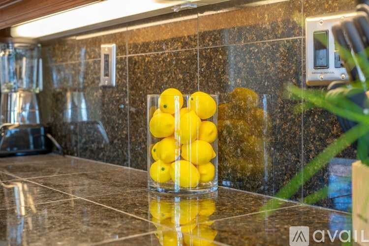 A glass container filled with yellow lemons on a counter.