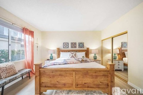 A bedroom with a wooden bed and a bench by the window.