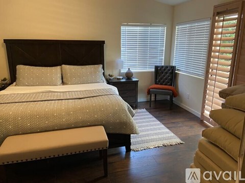A bedroom with a large bed and a chair with a red cushion.