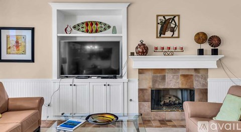 A living room with a fireplace, a television, and a surfboard decoration.
