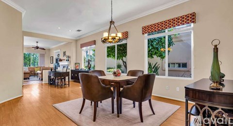 A dining room with a table set for four and a chandelier hanging from the ceiling.