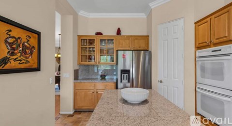 A kitchen with a bowl on the counter and a fridge in the middle.