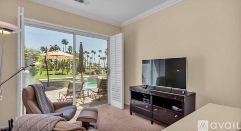 A living room with a television, chair, and sliding glass doors.