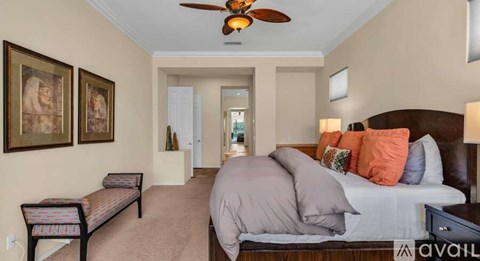 A bedroom with a bed, a bench, and a ceiling fan.
