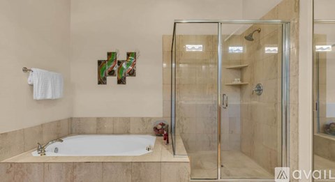 A bathroom with a tub and a glass shower door.