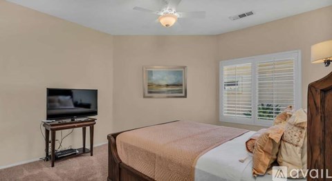 A bedroom with a bed, a television, and a painting on the wall.