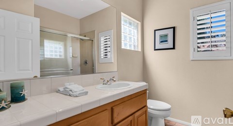 A bathroom with a white countertop and a framed picture on the wall.