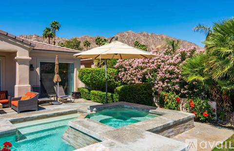 A pool surrounded by a patio with a table and chairs.