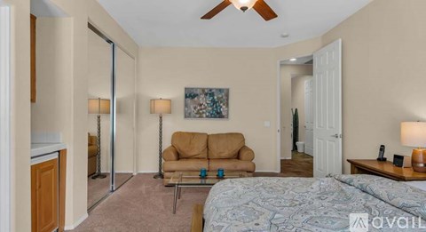 A bedroom with a bed, couch, and a painting on the wall.