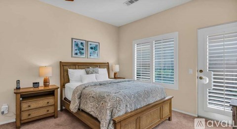 A bedroom with a bed, nightstand, and window with blinds.