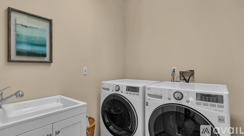 Two white front load washing machines are stacked on top of each other in a laundry room.