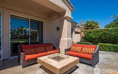A patio with a couch, table, and umbrella.