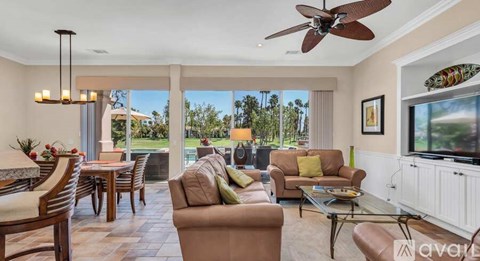 A living room with a brown couch and a ceiling fan.