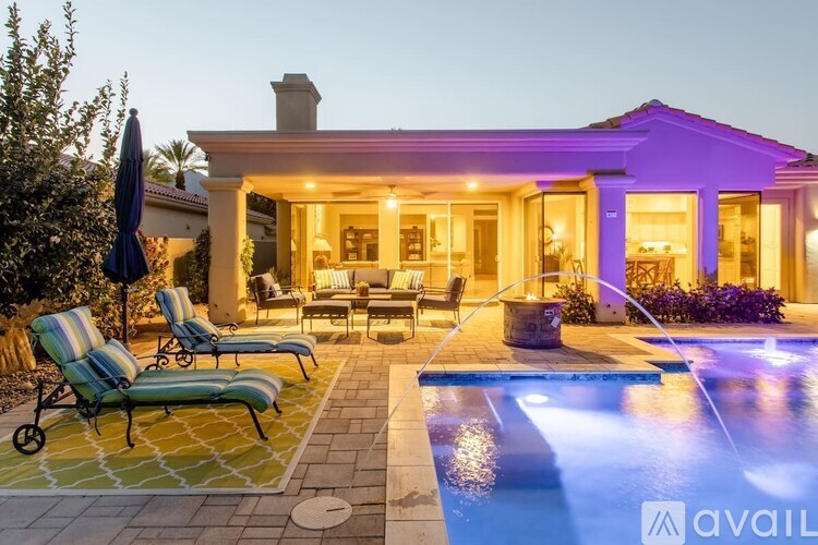 A house with a pool and lounge chairs in front.