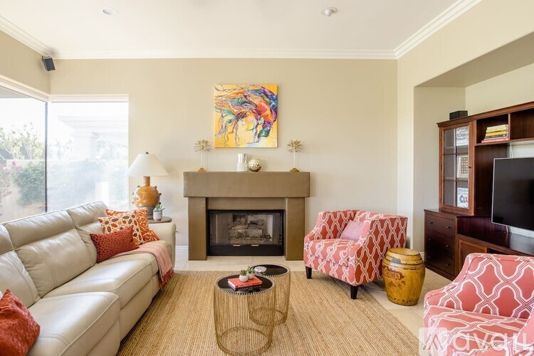 A living room with a fireplace and a painting above it.