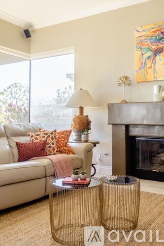 A living room with a white couch, a fireplace, and a painting on the wall.