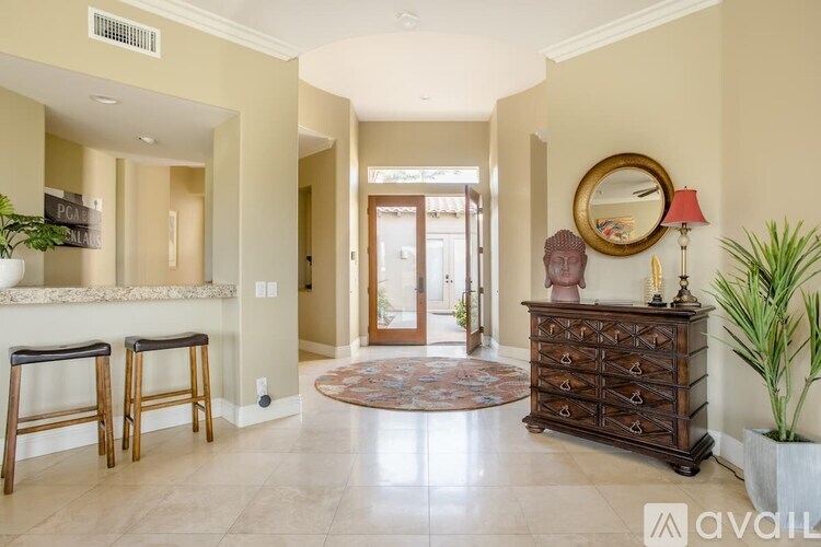 A hallway with a wooden dresser and a round mirror on the wall.