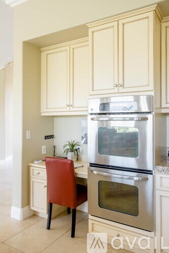 A kitchen with a red chair and a stainless steel oven.