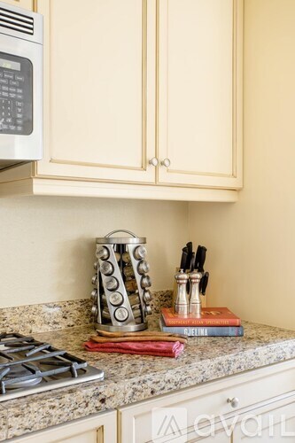 A kitchen counter with a stove, knives, and a stack of books.